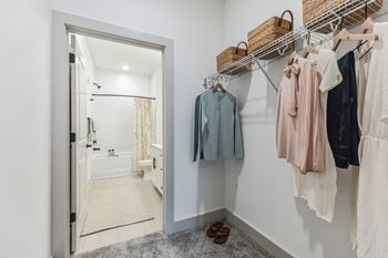 A closet with a mirror and a door to a bathroom